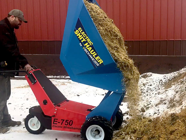 A Schweiss employee test the Electric Manure Hauler's dumping feature